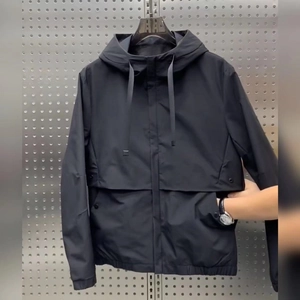 Detail of a black hooded windbreaker jacket with drawstring hood and snap button pockets