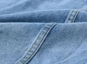 Macro detail of vintage blue denim jacket showing double yellow stitching and twill texture