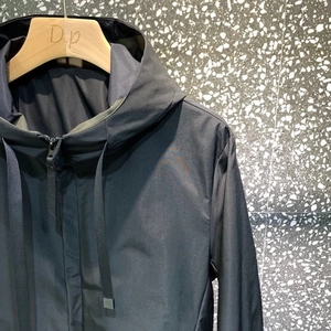 Detail of hooded windbreaker jacket with metal-tipped drawstrings and premium zipper