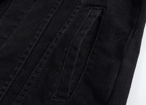Dettaglio della cucitura rinforzata e trama denim twill su una giacca nera