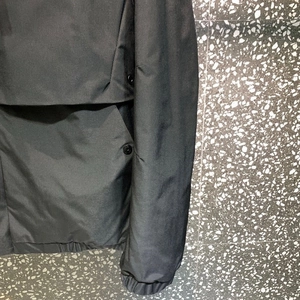 Detail of black workwear jacket showing snap buttons and elastic cuffs with windproof fabric