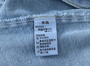 Detailed close-up showing the laundry care label on the blue denim jacket sleeve