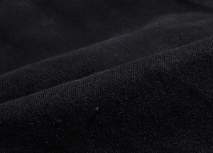 Primo piano del tessuto denim nero con trama twill ad alta densità e pieghe morbide sulla giacca