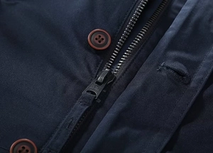 Detailed close-up of premium metal zipper and brown button on navy blue men jacket