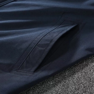 Detail view of the side pocket and fine stitching on the navy blue windbreaker jacket