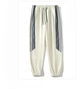 Detailed view of beige joggers with side stripes and elastic drawstring waistband