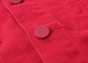 Macro della trama di una giacca di jeans rossa con bottone metallico e cuciture fini