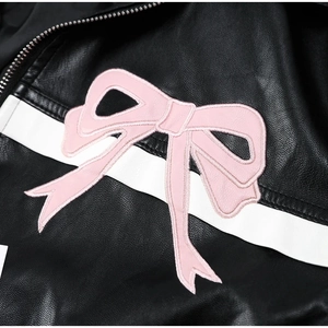 Macro detail of faux leather jacket featuring a pink bow embroidery and white stripes