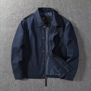 Detail of navy blue windbreaker jacket featuring zipper, buttons and brand inner label