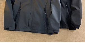 Detailed view of adjustable velcro cuffs and waterproof zipper pocket on technical jacket