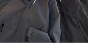 Detail of waterproof black techwear jacket showing velcro cuff and dot pattern collar