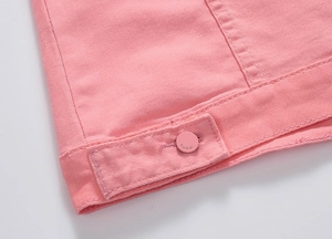 Dettaglio dell'orlo della giacca di jeans rosa con bottone metallico e cinturino regolabile