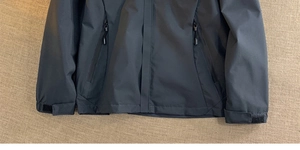 Detail of dark gray outdoor jacket with waterproof zippers and adjustable velcro cuffs