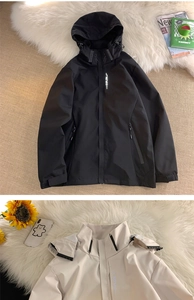 Detail view of EXPLORE text on a functional hooded windbreaker jacket in black and beige