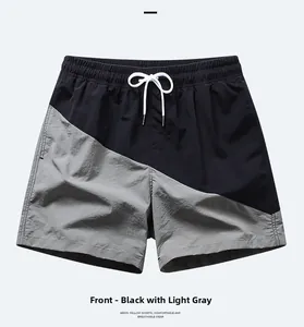 Detailed view of men's quick-dry beach shorts with black and grey patchwork and drawstring