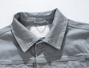 Dettaglio ravvicinato del colletto e delle cuciture della spalla di una giacca denim grigia