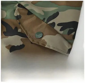 Gros plan d'une veste camouflage montrant la poche en biais et le bouton-pression