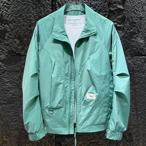 Detail of mint green lightweight jacket showing logo label and fabric texture