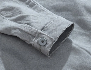 Dettaglio del polsino della giacca di jeans grigia con bottone inciso e cuciture fini