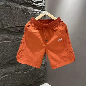 Detail of light orange quick-dry men's shorts with drawstring waist and white logo print