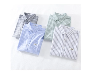 Flat lay of four neatly folded striped cotton shirts in grey, blue, green, and white