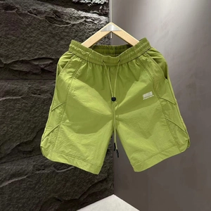 Detailed view of lime green shorts with elastic waistband and barcode print design