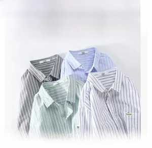 Detailed view of stacked striped men's shirts in gray, light blue, and pale green colors