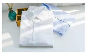 Detail shot of folded linen shirts in white and light blue with standard collar and texture