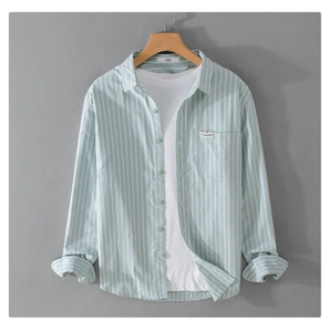 Detailed close-up of light green striped cotton shirt texture and chest pocket label