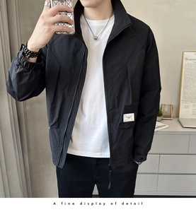 Detailed view of lightweight black men's jacket with asymmetric seams and letter patch