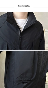 Detailed view of black urban jacket featuring high collar zipper and metal D-ring buckle