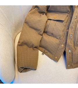 Detailed close-up of dark brown quilted winter jacket with metal buttons and cord adjusters