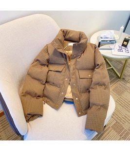 Detail of short brown padded jacket with wave quilting and drawstring hem on a sofa