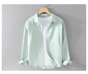 Close-up of mint green linen shirt layered over a white t-shirt on a wooden hanger