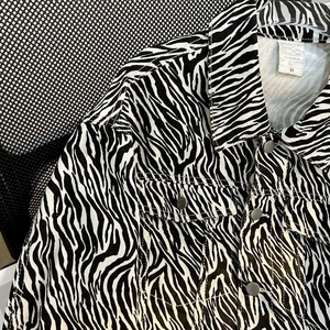 Detail shot of zebra print denim jacket featuring chest pockets and metal buttons