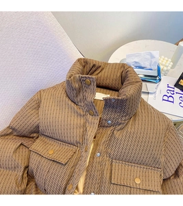 Detail of brown quilted jacket featuring a high stand collar and metal snap buttons