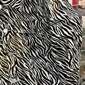 Close-up of zebra pattern denim jacket showing silver metal buttons and twill texture