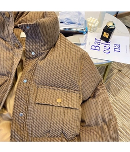 Detail of high stand collar and metal snap buttons on a brown quilted winter puffer jacket