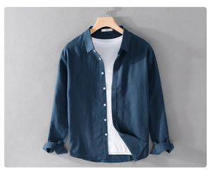Detail of navy linen shirt layered over white t-shirt on a wooden hanger against grey wall