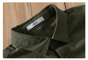 Close-up of dark green work shirt collar with woven size label on a wooden background