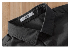 Close-up of charcoal grey cotton shirt collar with size tag and matching button detail