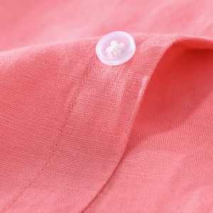 Close-up of coral linen shirt showing breathable fabric texture and resin button detail
