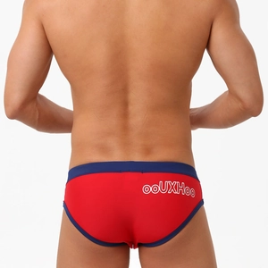 Rear view of red men's swim briefs with navy trim and white logo on white background