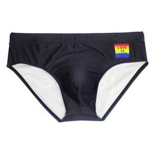 Detail van de zwarte zwembroek met elastische tailleband en Love Is Love regenboogpatch
