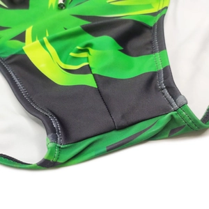 Detailed close-up of tropical green leaf print swimwear fabric with reinforced stitching