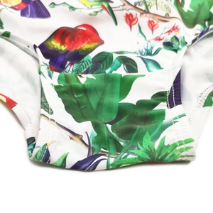 Macro shot of tropical parrot and floral print on white stretch fabric with precise stitching