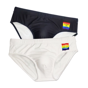 Detail van laag uitgesneden zwemslip met regenboog Love Is Love patch en trekkoord taille