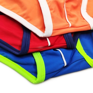 Dettaglio di tre slip da nuoto uomo con design color block in arancione, rosso e blu