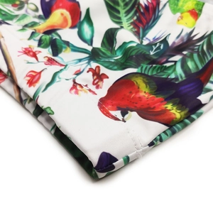 Détail de l'imprimé floral et perroquet tropical sur un maillot de bain blanc