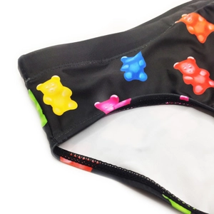 Detailed close-up of men's swim briefs featuring colorful gummy bear patterns on black fabric
